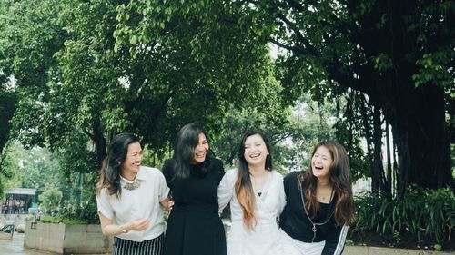 Young women standing against trees