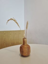 Close-up of vase on table against wall at home