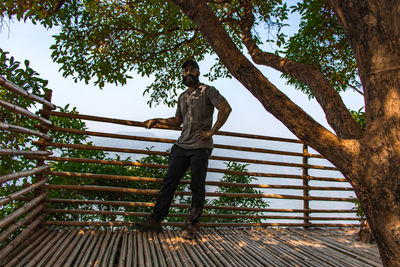 Me standing by railing against trees at mawlynnong village