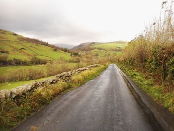 Road amidst green landscape against sky