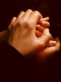 Close-up of man holding hands over black background