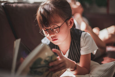 Young woman using mobile phone while sitting on book