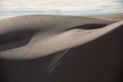 Sand dunes at desert against sky