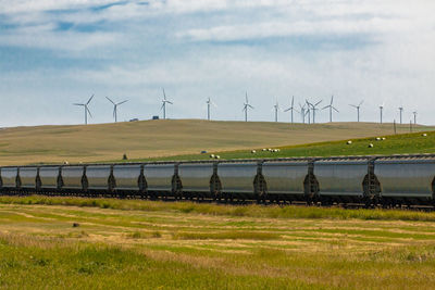 Windmills on field against sky