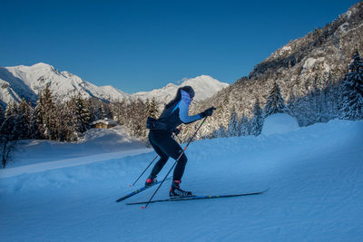 Full length of person skiing on snowcapped mountain against blue sky