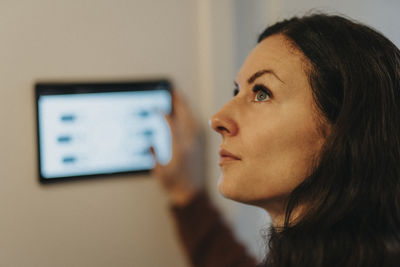 Mature woman controlling temperature of room through digital tablet at home