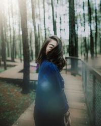 Side view portrait of young woman standing amidst trees