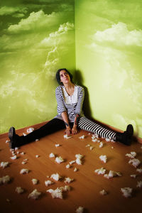 Full length of young woman sitting on flooring