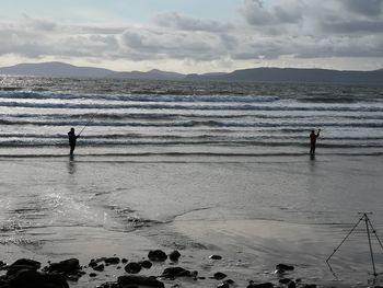 People fishing in sea against sky