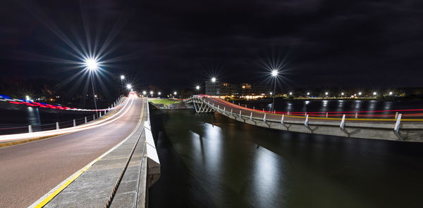 Light trails on road in city against sky at night