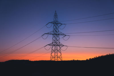Low angle view of silhouette electricity pylon against sky during sunset
