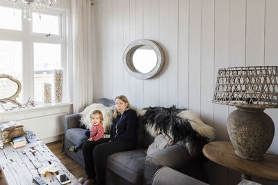 Grandmother sitting with granddaughter on sofa at home