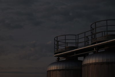 Low angle view of beer tanks against sky