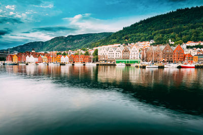 Buildings by river against sky in city