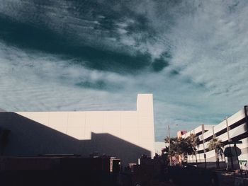 People walking in city against cloudy sky