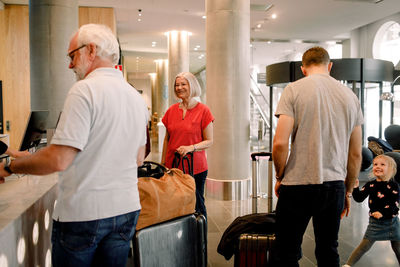 Smiling family standing at reception in hotel