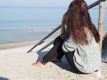 Rear view of woman sitting on beach