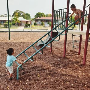 Side view of boy standing on slide at playground