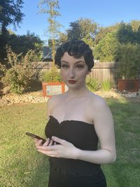 Portrait of young woman standing by tree