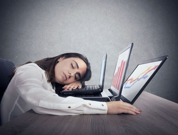 Young woman using laptop while sitting on bed at home