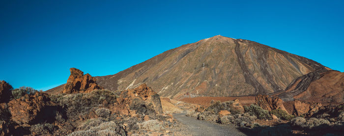 Scenic view of arid landscape against clear blue sky