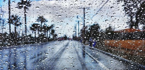 Road seen through wet window in rainy season