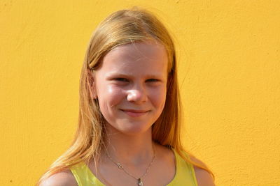 Portrait of smiling girl against yellow wall