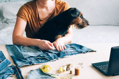 Midsection of woman with dog on bed at home