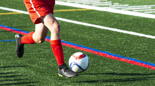 Man playing soccer ball on grass