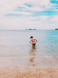 Rear view of man standing in sea against sky