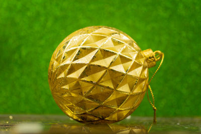 Golden christmas bauble on green sparkling background.