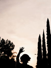 Silhouette man hand against sky during sunset