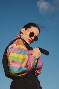 Low angle view of woman in sunglasses against blue sky