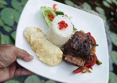 Close-up of hand holding food in plate