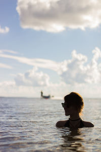 Young woman swimming in sea against sky