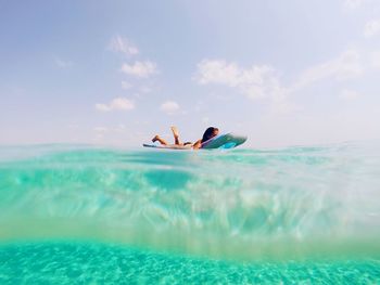 Low angle view of woman on raft in turquoise sea