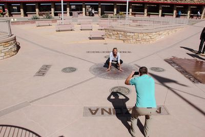 High angle view of man photographing woman at historical building on sunny day