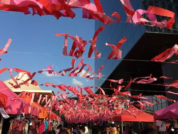 Low angle view of multi colored flags hanging against sky