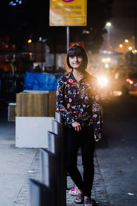 Woman standing on illuminated street at night