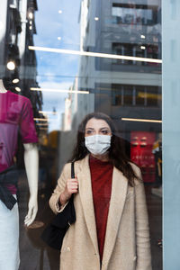 Woman wearing mask standing by clothing store