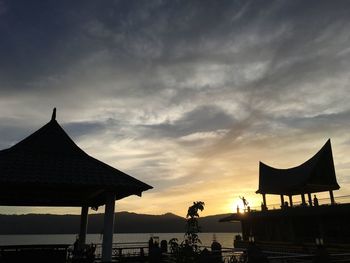 Silhouette built structure on beach against sky during sunset