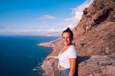 Portrait of young woman standing against mountain