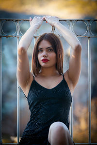 Portrait of young woman with arms raised