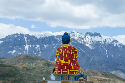 Rear view of man looking at snowcapped mountain against sky