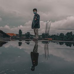 Man standing in lake against sky