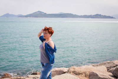 Side view of man standing on rock at beach