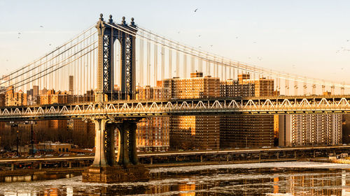 Manhattan bridge over east river against sky in city