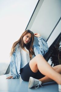 Portrait of young woman sitting against window