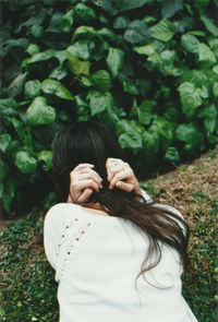 Rear view of woman bending against plants