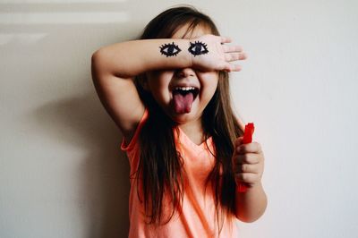 Front view of cute girl hand with eyes drawing against white wall